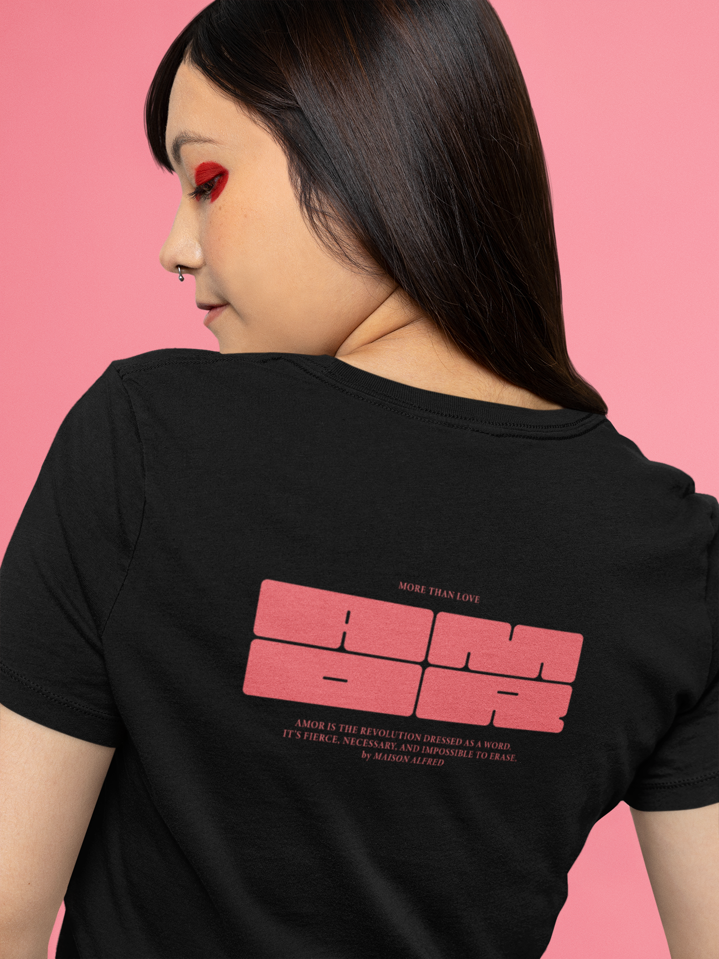 Person wearing a black t-shirt with red text on the back against a pink background